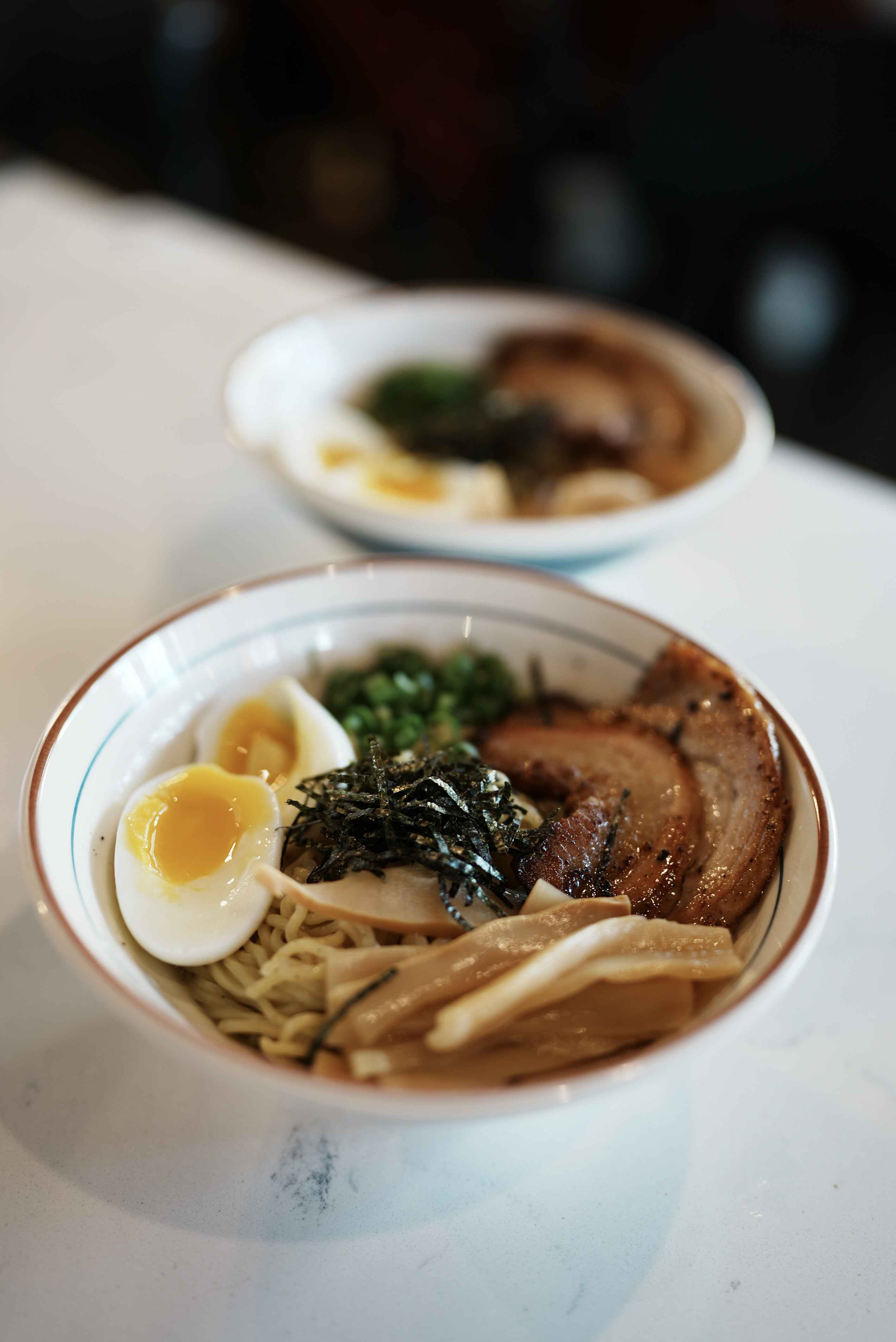 A bowl of aburasoba brothless ramen topped with a soft egg, chashu pork, bamboo shoots, and nori at Slurp Station in Seattle