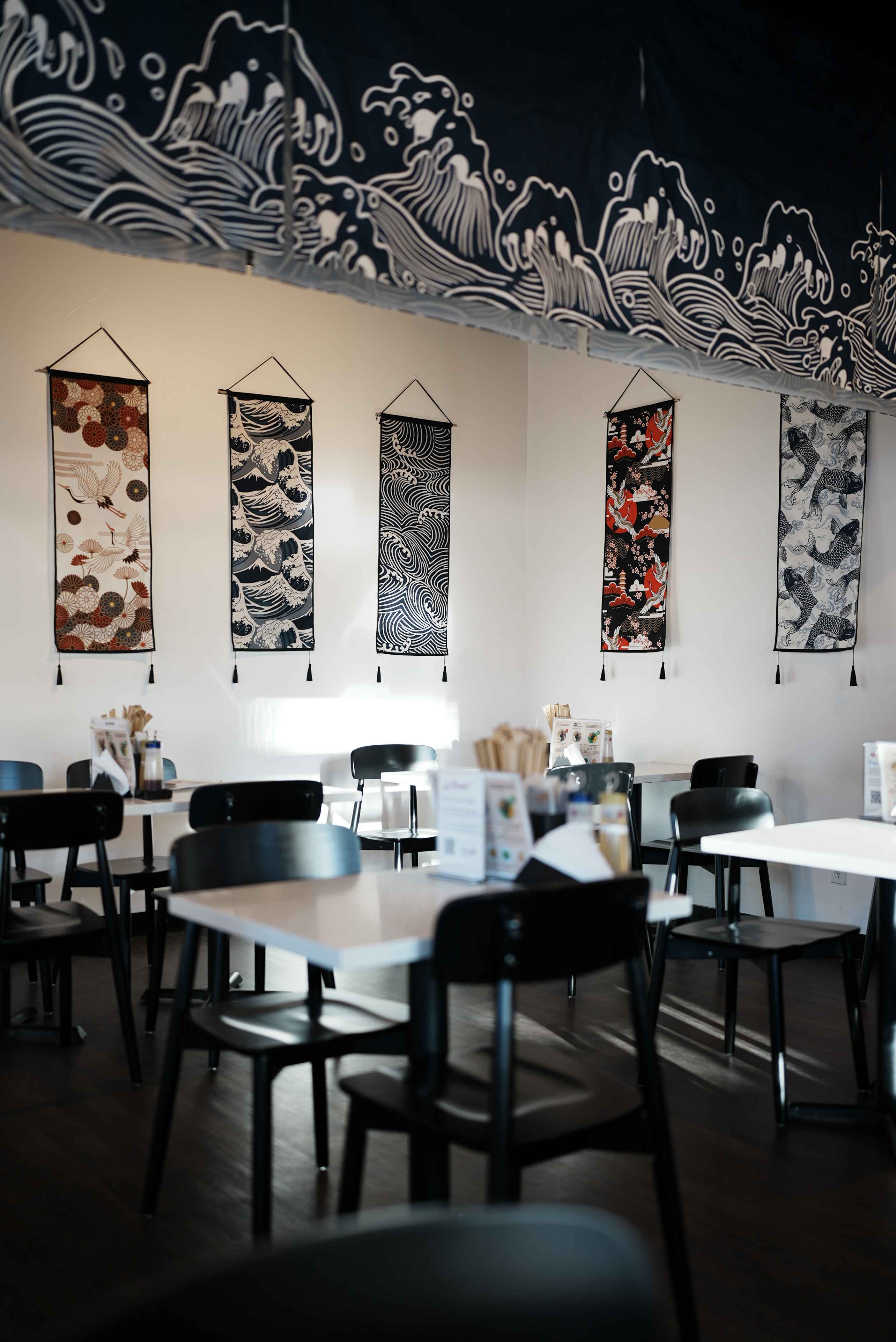 Dining room at Slurp Station Aburasoba in Seattle's U District, with Japanese wave banners on the wall